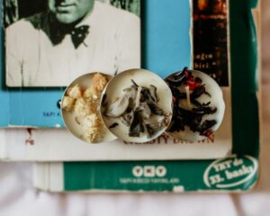 Three aromatic wax candles with herbs placed on vintage books for a cozy atmosphere.