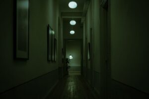 Explore the moody atmosphere of a narrow corridor with green lighting and hanging lamps.