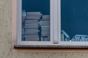 View of stacked books inside a window from the outside, showcasing a home library.