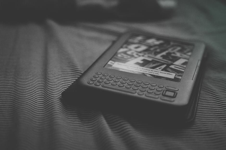 Black and white e-reader resting on patterned bedding, focusing on technology and reading.