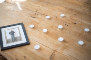 A framed photo with candles on a wooden table evokes remembrance and reflection.
