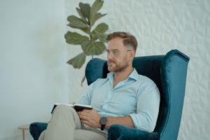 Male counselor in a modern office chair taking notes, promoting mental health awareness.