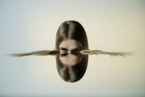 A conceptual portrait of a woman's reflection in water, offering tranquil and artistic vibes.